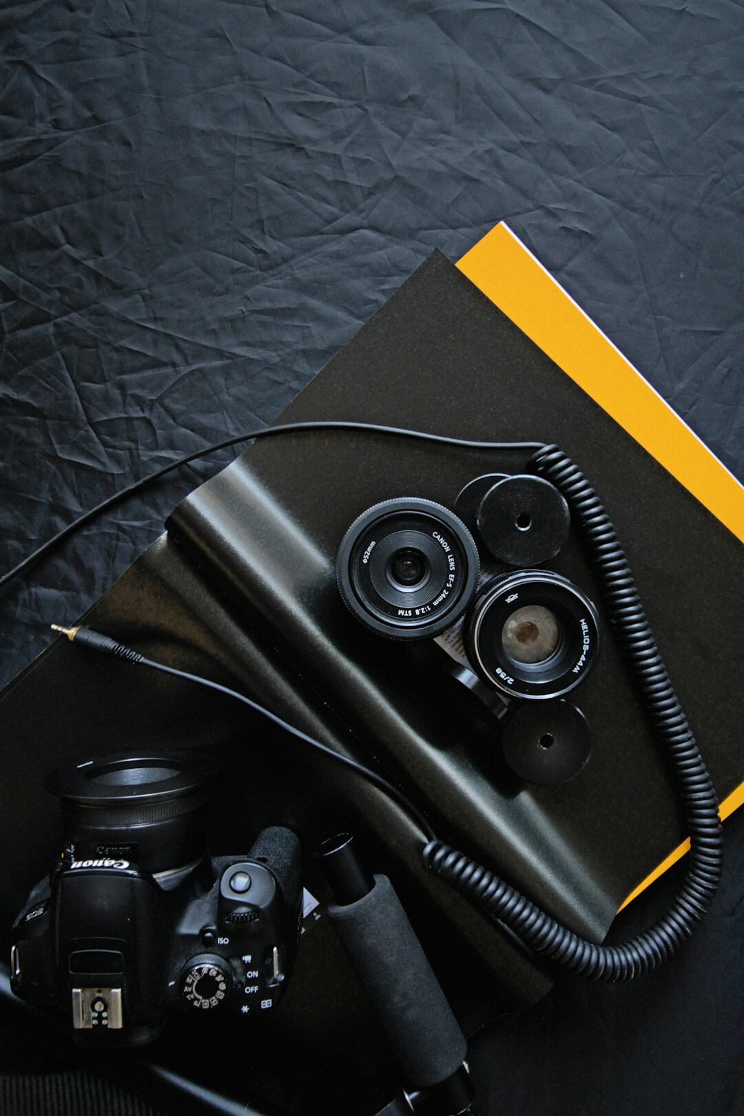 Flatlay of documentary photography equipment including camera, lenses and notebook